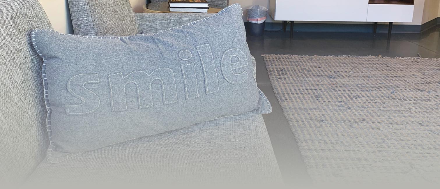 A grey pillow with the wood smile on it.