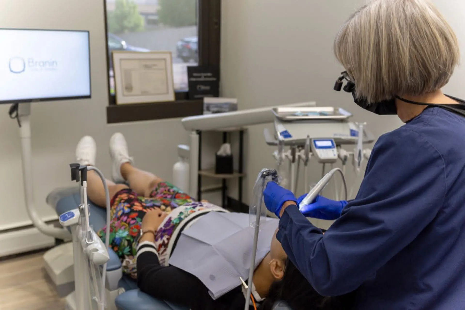 A staff member cleaning the teeth of a patient