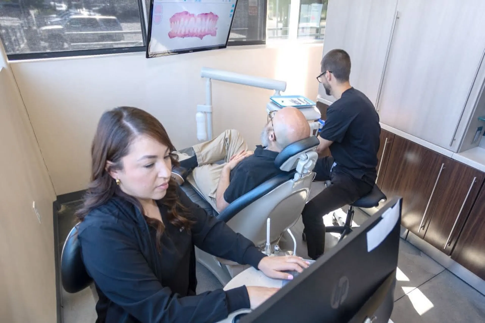 A hygienist and doctor working on a patient in a dental chair