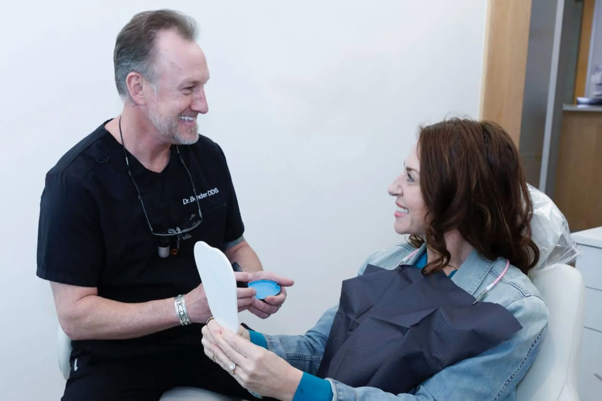 Dr. Bender with a patient in a dental chair holding a mirror