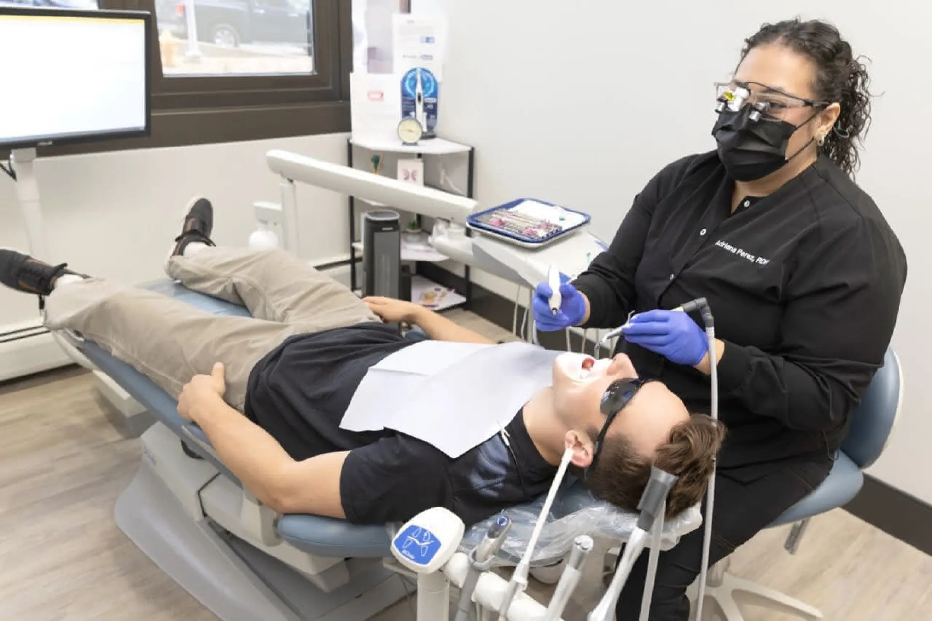 A patient in a dental chair wearing eye protection