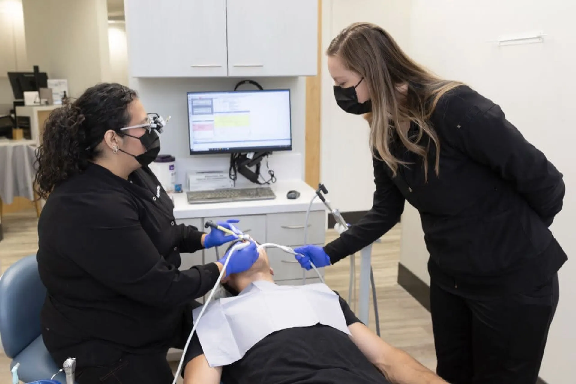 A hygienist and a dental assistant working on a patient 