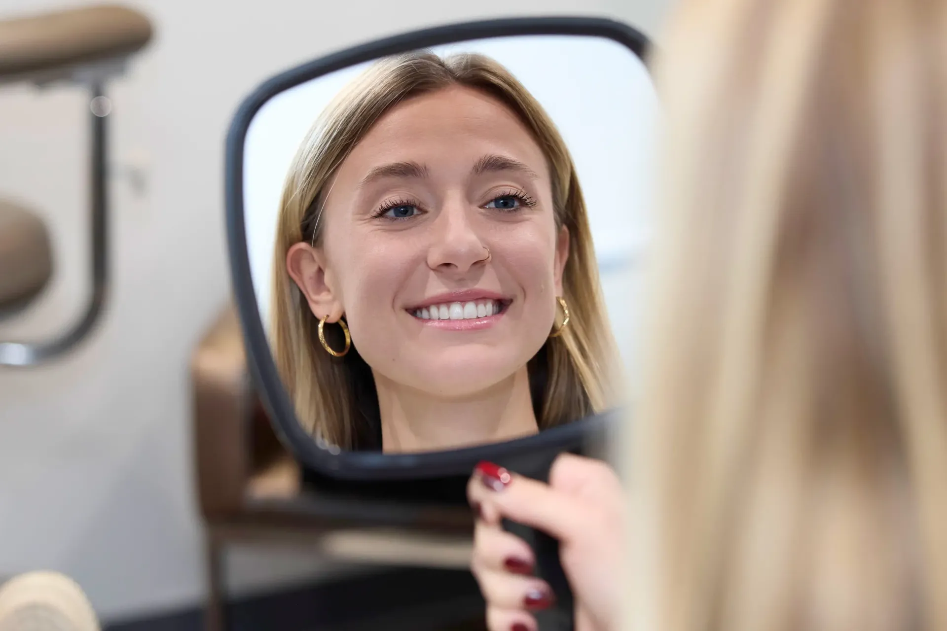 A patient looking at themselves in a hand mirror