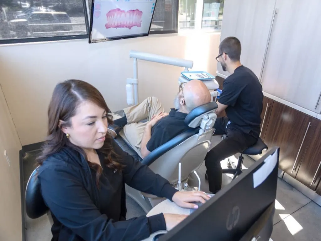 A hygienist and doctor working on a patient in a dental chair