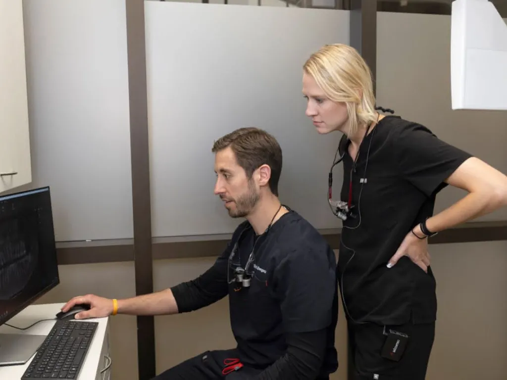 Staff stands behind doctor at computer reviewing patients X-ray