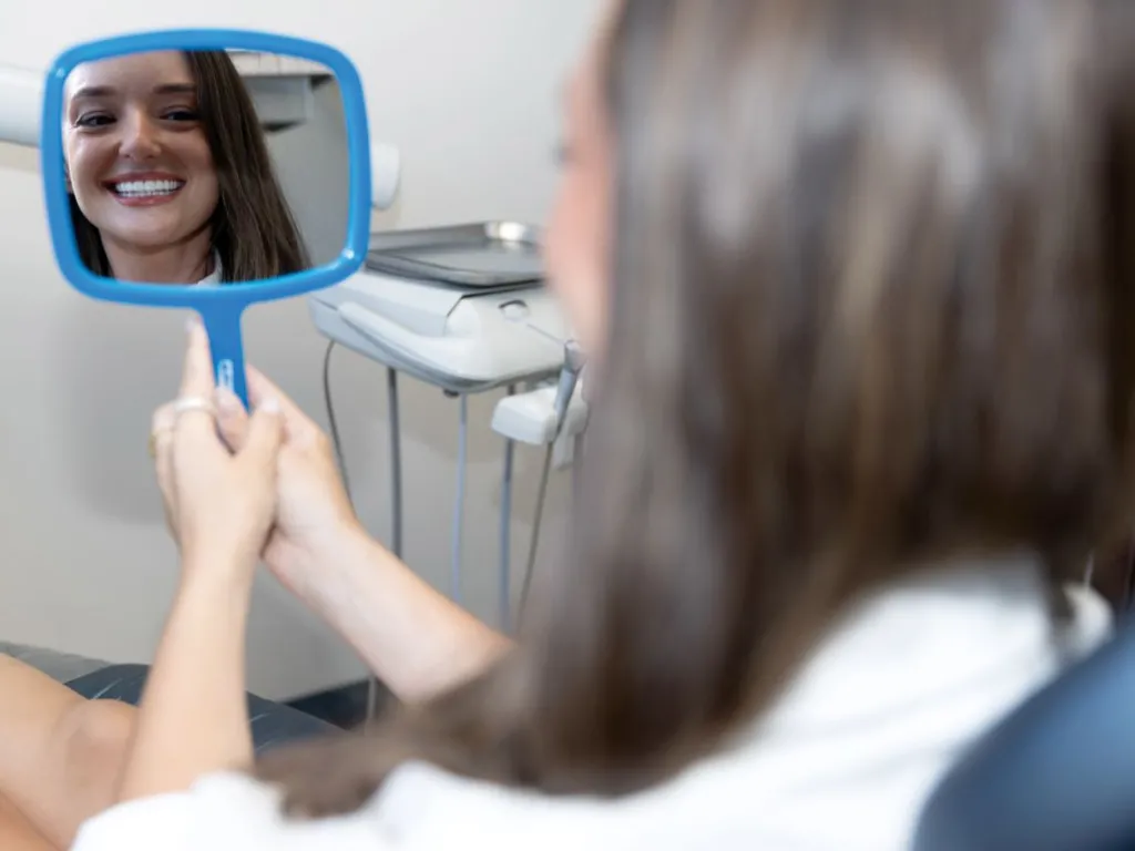 Patient holding blue mirror smiling