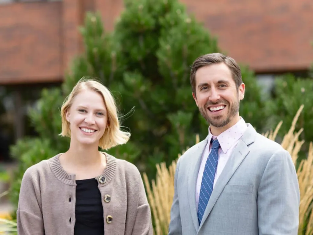 Two doctors standing in front of prairie grass smiling