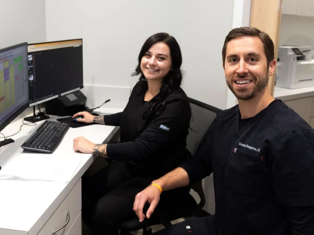 A dental assistant at a computer with a dentist off to the side