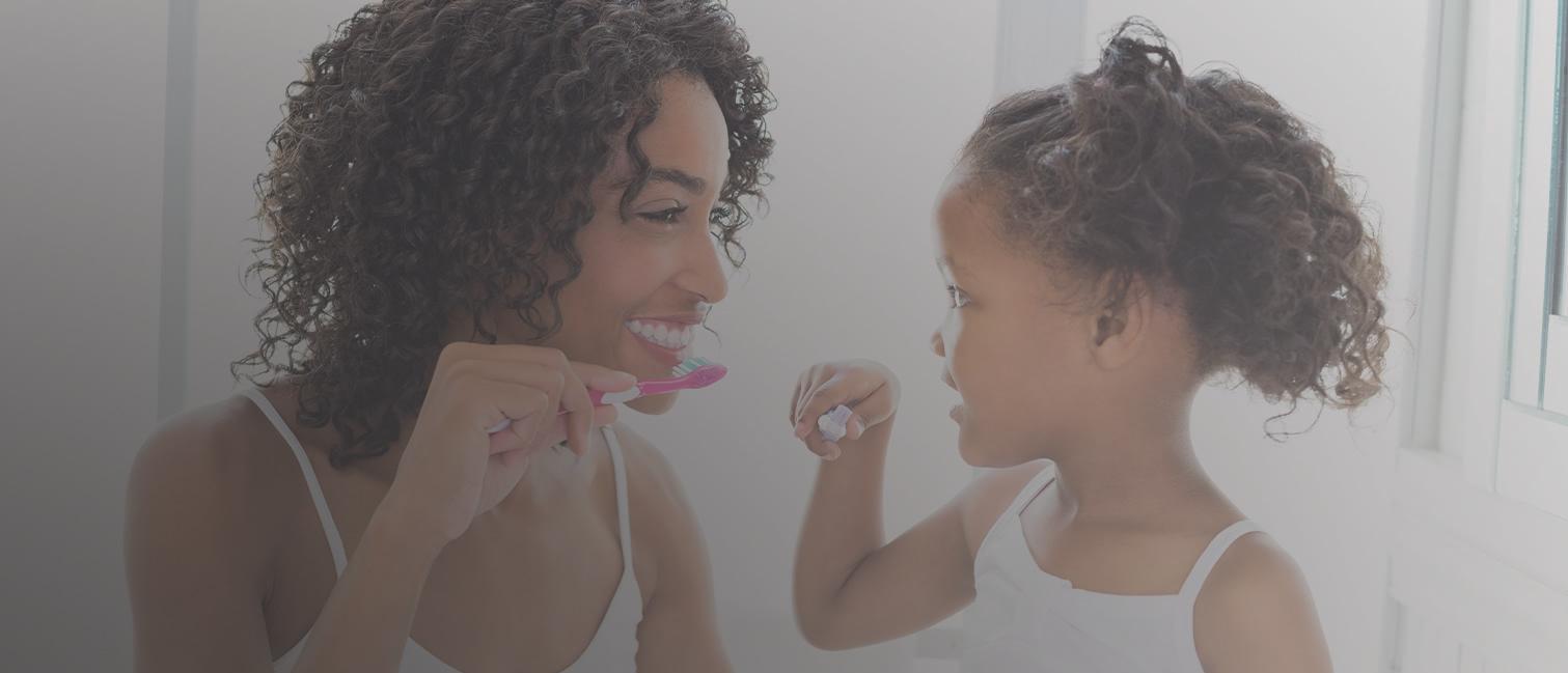 A mother brushing her teeth with her daughter