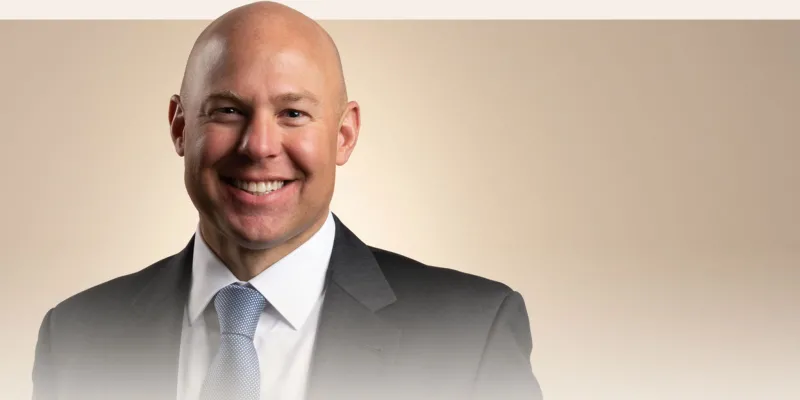 A portrait of Scott Dudley in a black suit